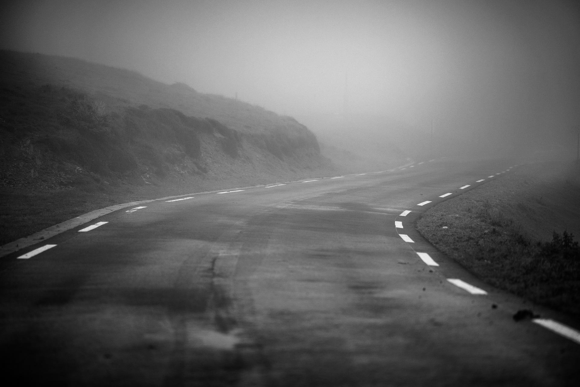 Brume — route de montagne légèrement sinueuse disparaissant dans le brouillard